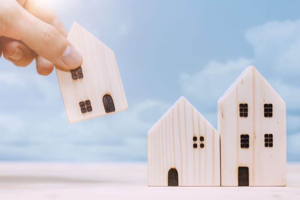 A hand placing a house model with another house models in the concept of house move