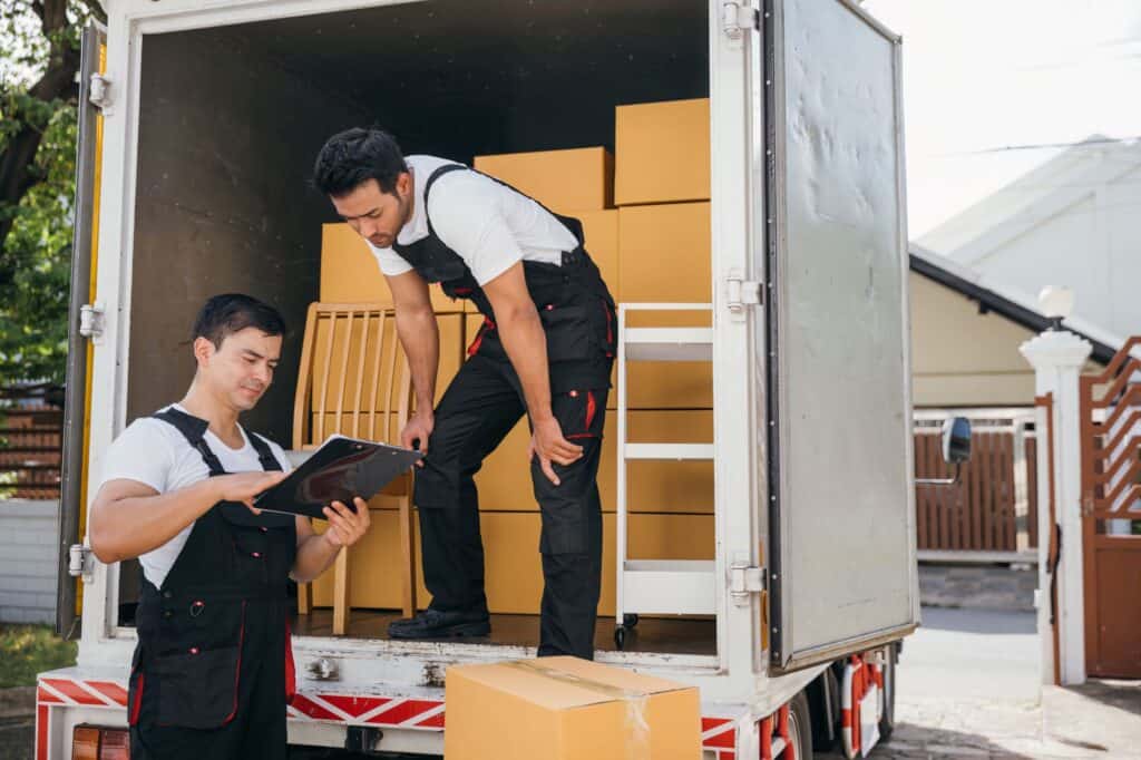 A house movers team checking their list at the back of the van