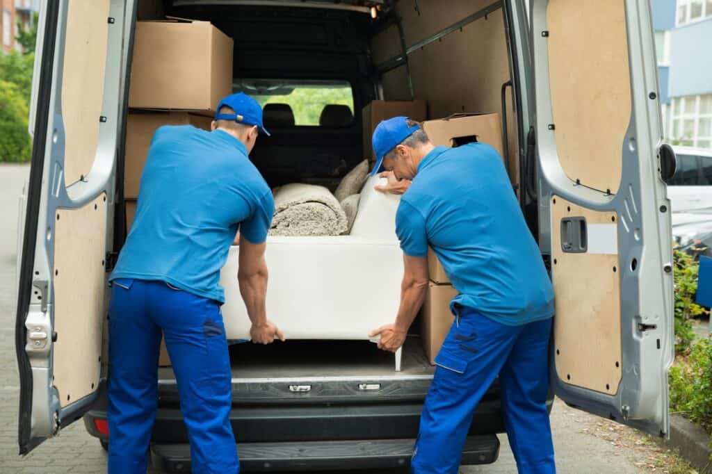 The movers placing the sofa inside the van.