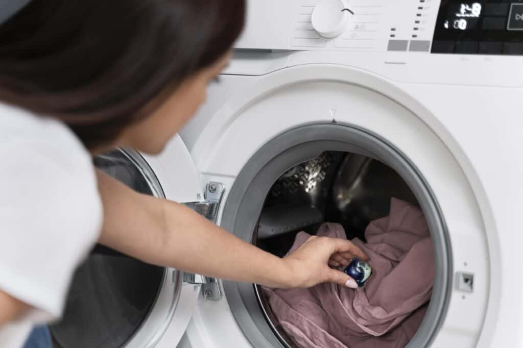 A woman putting a laundry capsule into the washer