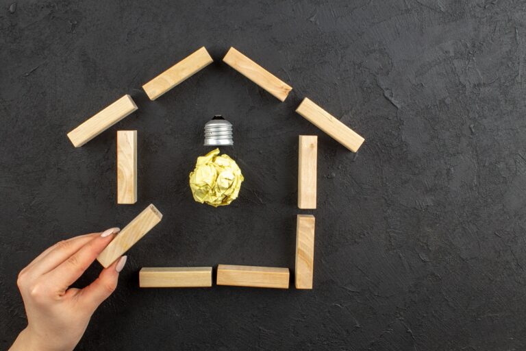 Wooden blocks forming a house with a mock light bulb in the concept of 'changing address and updating utilities after moving to Wood Green'.